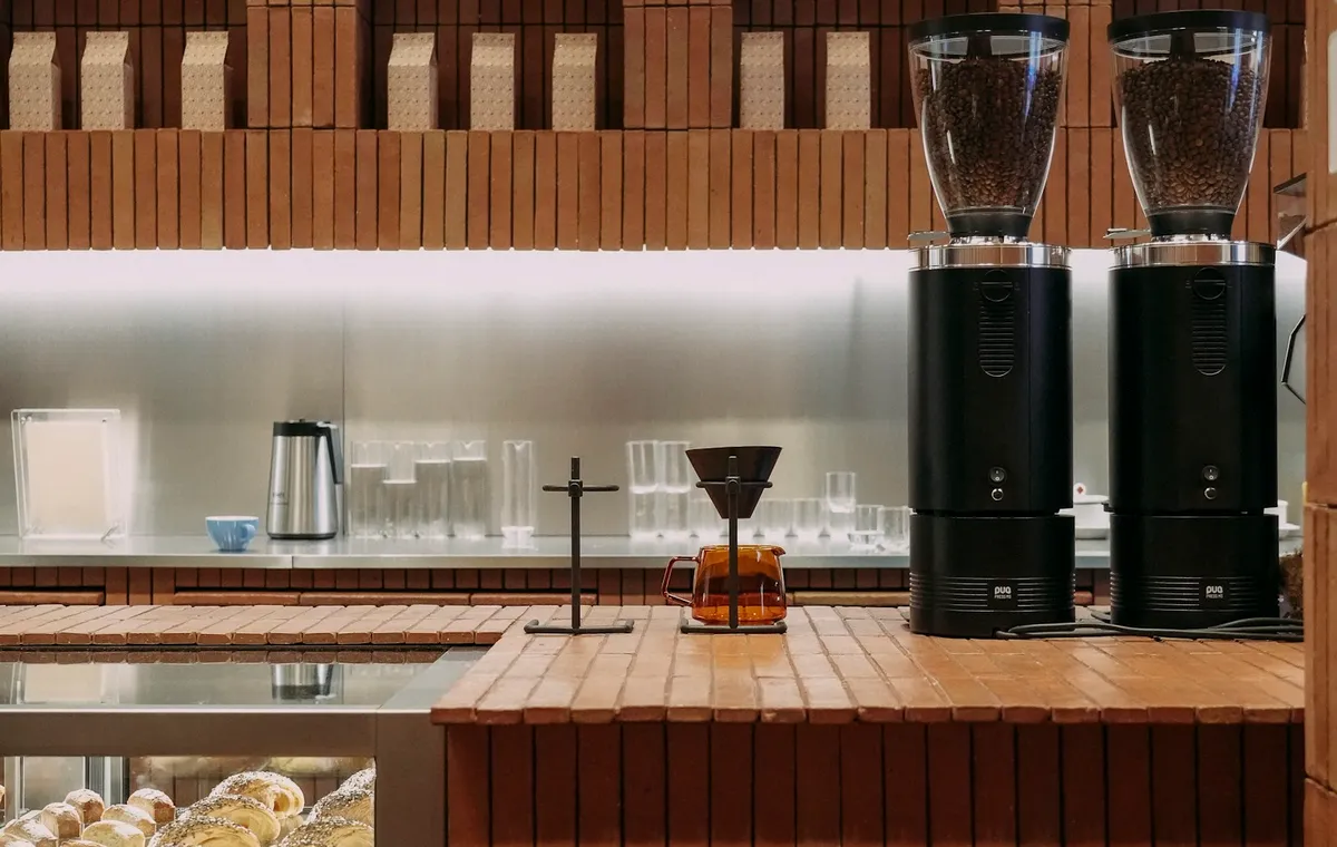 Mostrador de madera con molinos de café y pan detrás del cristal