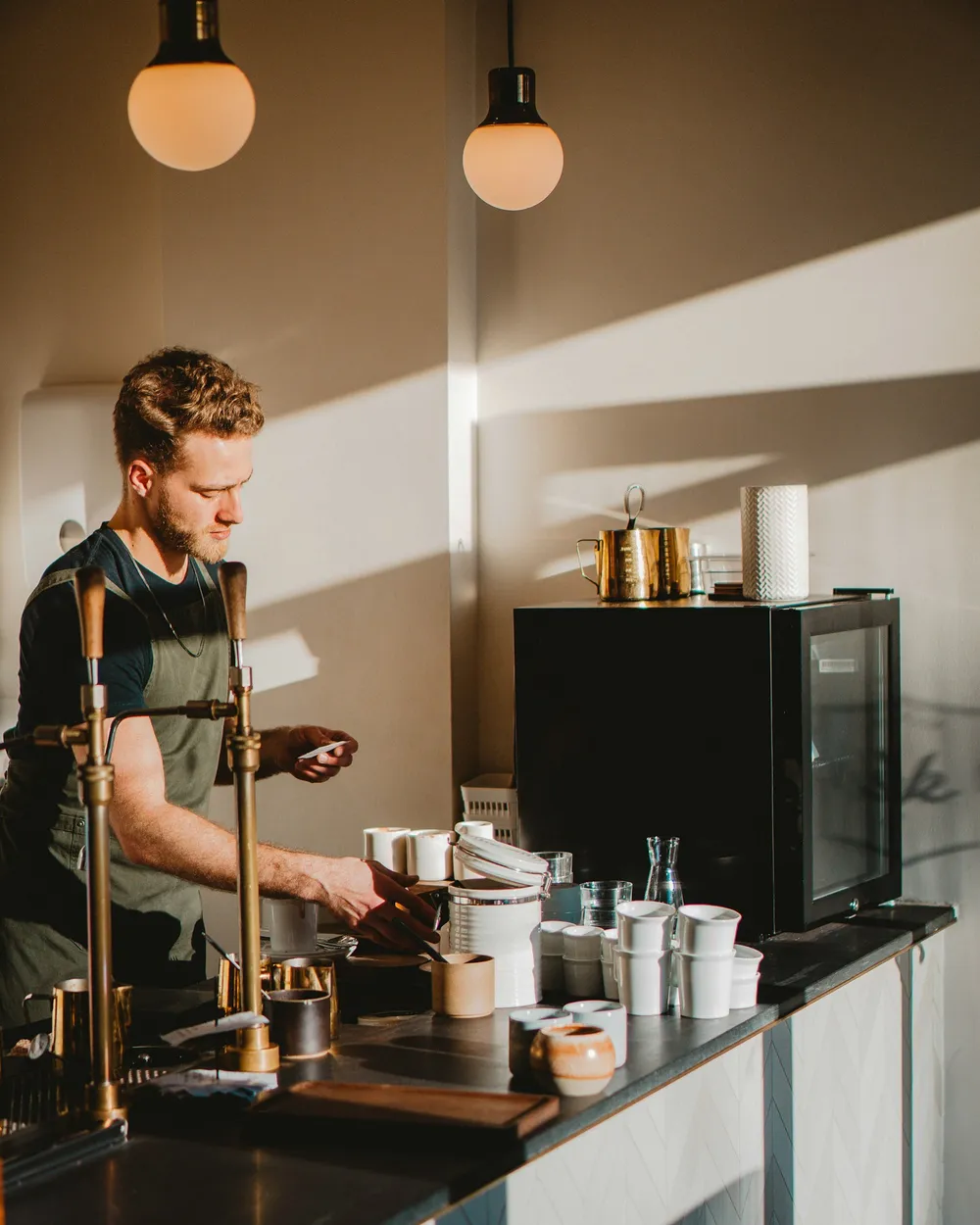 Barista preparando tazas en la barra, con luz de mañana