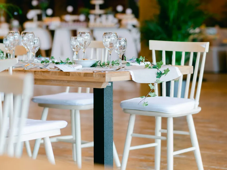 Mesa con sillas blancas y arreglo verde