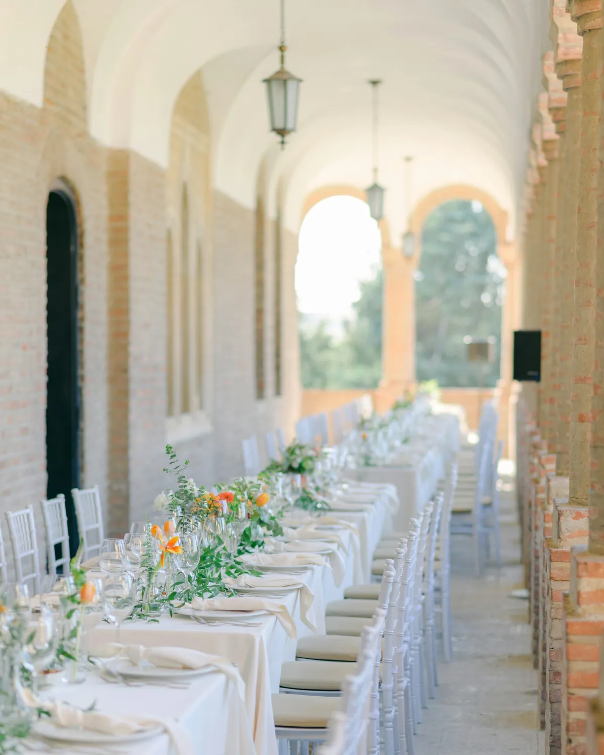 Mesa larga de boda con flores blancas y azules bajo una arcada